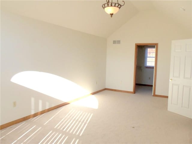 carpeted spare room with vaulted ceiling