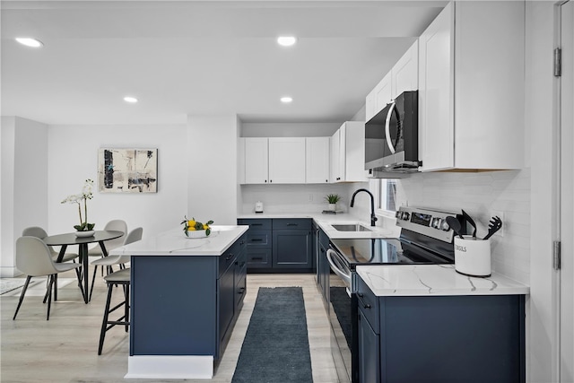 kitchen with a kitchen island, light hardwood / wood-style flooring, stainless steel appliances, sink, and white cabinets