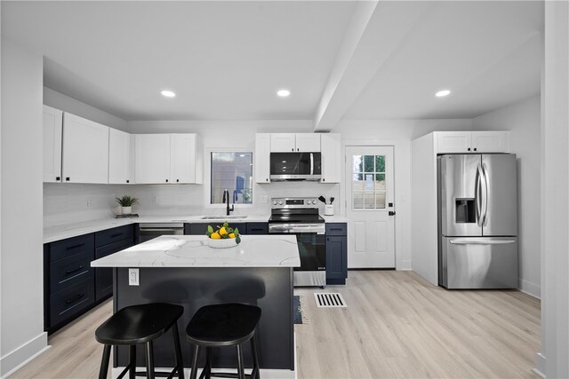 kitchen featuring appliances with stainless steel finishes, a breakfast bar, a center island, and light hardwood / wood-style floors