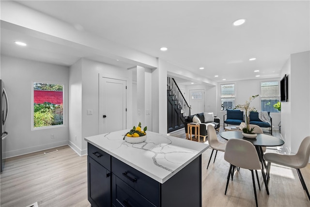 kitchen featuring a kitchen island, light hardwood / wood-style flooring, and light stone counters