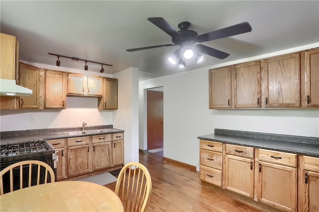 kitchen with sink, rail lighting, gas range oven, light hardwood / wood-style floors, and ceiling fan