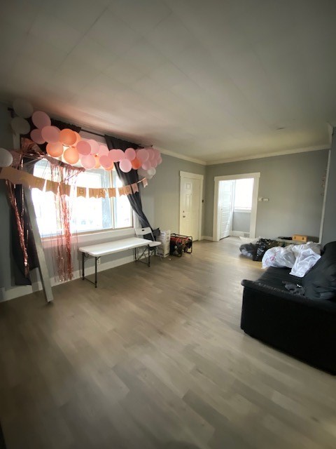 unfurnished living room featuring ornamental molding and hardwood / wood-style floors