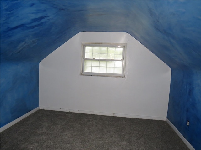 additional living space with lofted ceiling and dark colored carpet