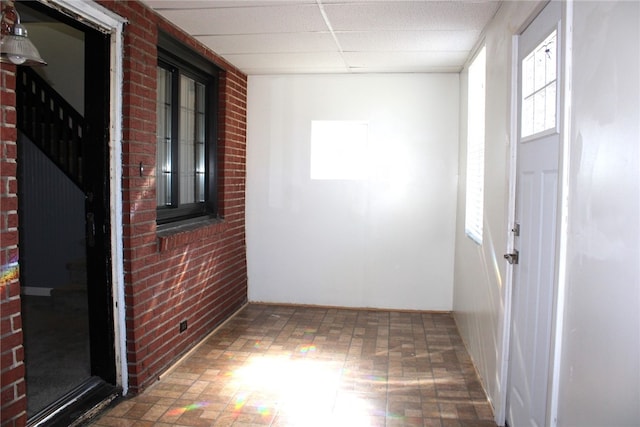 interior space with brick wall and a drop ceiling