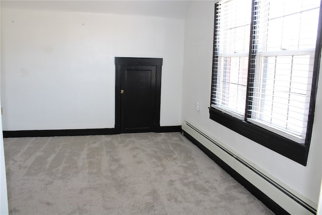 unfurnished room featuring light carpet and baseboard heating