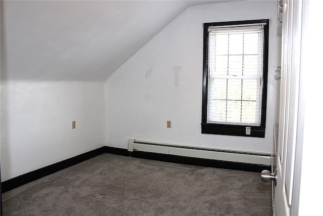 additional living space with a baseboard radiator, vaulted ceiling, and dark colored carpet