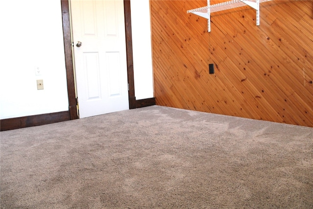 carpeted spare room with wooden walls