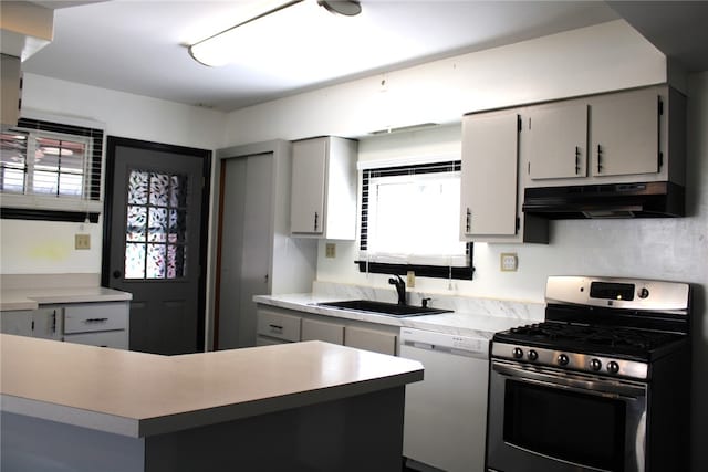 kitchen with sink, white dishwasher, stainless steel gas range, and gray cabinetry