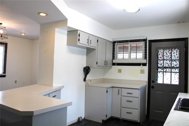 kitchen with gray cabinets, kitchen peninsula, plenty of natural light, and dark hardwood / wood-style flooring