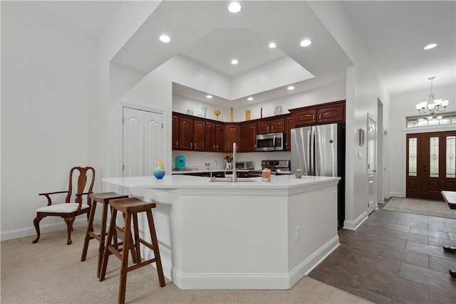 kitchen with appliances with stainless steel finishes, sink, a kitchen bar, an inviting chandelier, and a center island with sink