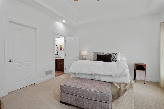 bedroom with connected bathroom and light carpet