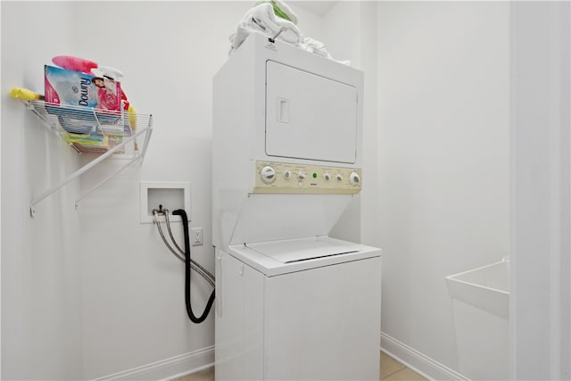 clothes washing area featuring stacked washer and dryer and light tile patterned floors