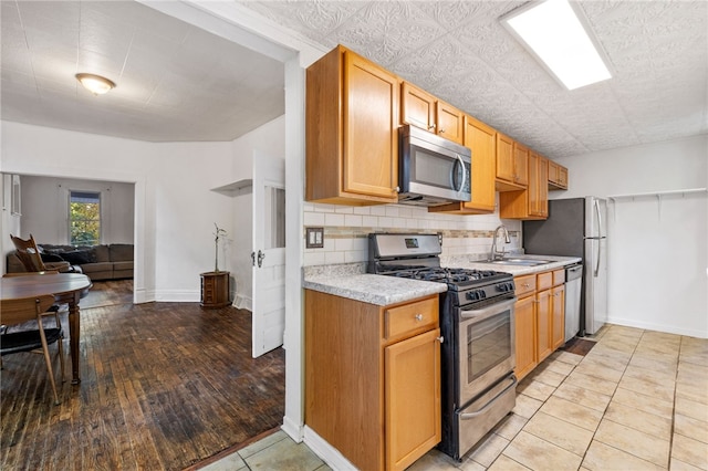 kitchen featuring sink, appliances with stainless steel finishes, light hardwood / wood-style flooring, and tasteful backsplash