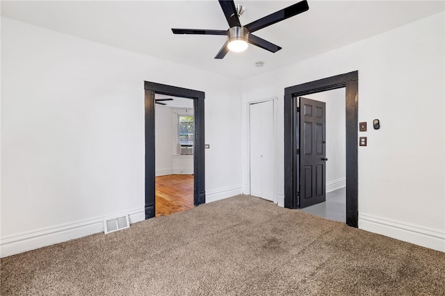 unfurnished bedroom featuring ceiling fan, cooling unit, and dark colored carpet