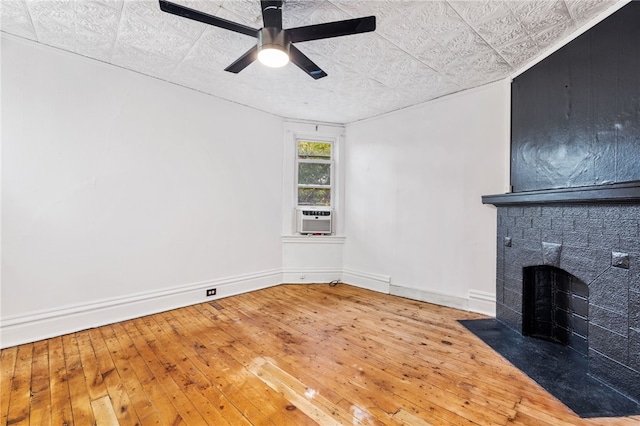 unfurnished living room with hardwood / wood-style floors, cooling unit, a brick fireplace, and ceiling fan