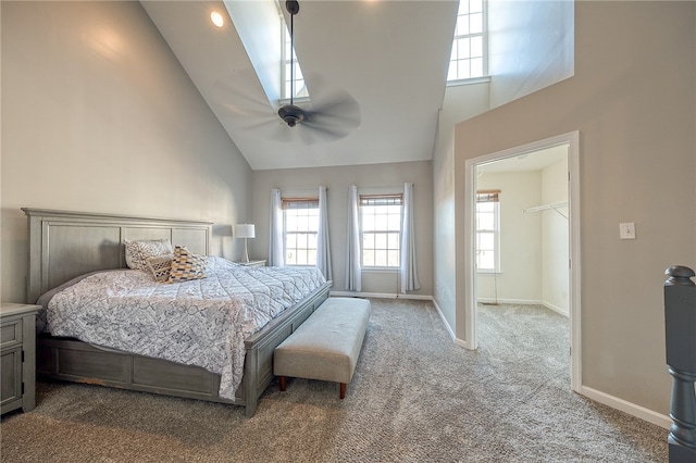 carpeted bedroom featuring a closet, ceiling fan, high vaulted ceiling, and a walk in closet