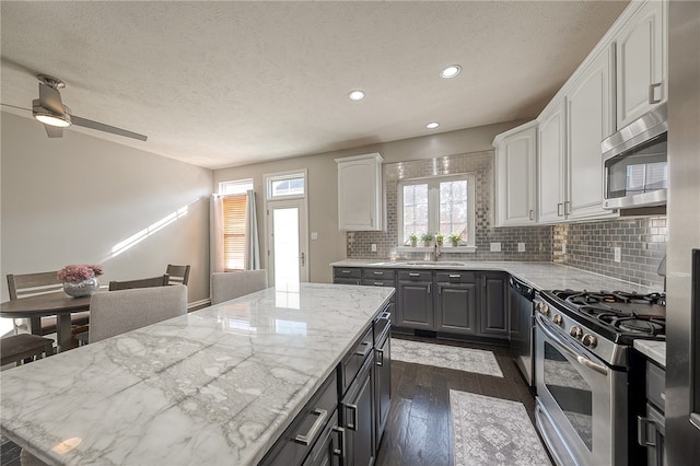 kitchen with sink, light stone counters, appliances with stainless steel finishes, and dark hardwood / wood-style flooring