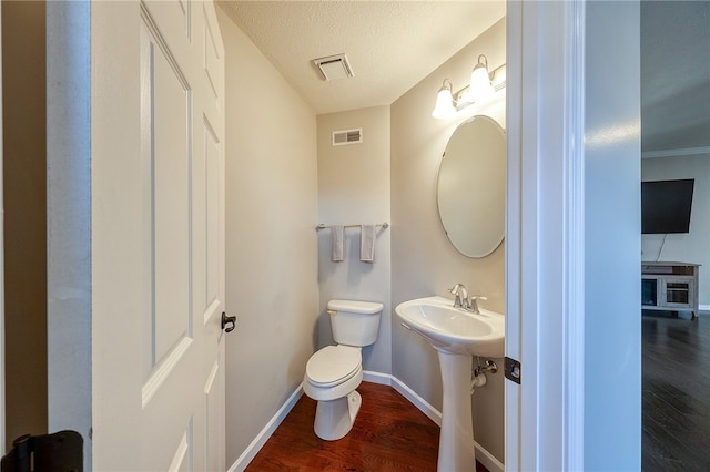 bathroom featuring a textured ceiling, hardwood / wood-style flooring, and toilet