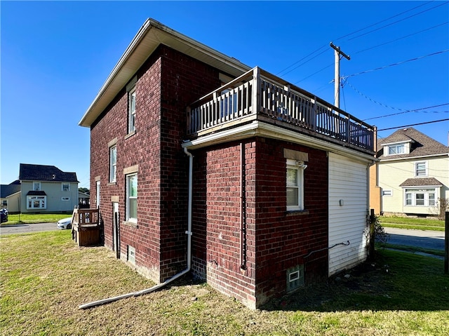 view of home's exterior with a balcony and a lawn