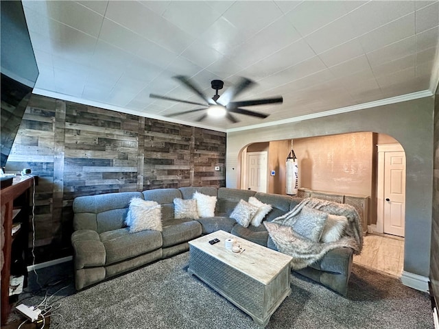 carpeted living room featuring ornamental molding, wooden walls, and ceiling fan