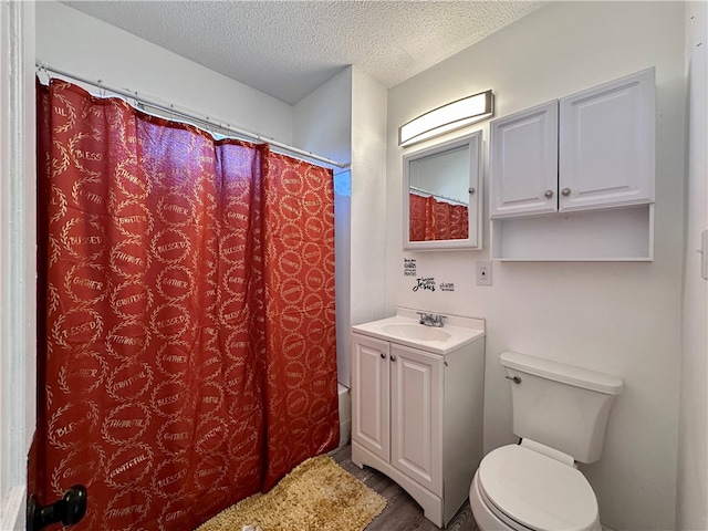 bathroom with a textured ceiling, hardwood / wood-style flooring, toilet, vanity, and curtained shower