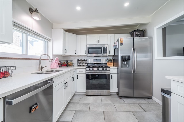 kitchen featuring tasteful backsplash, sink, light tile patterned flooring, stainless steel appliances, and white cabinets