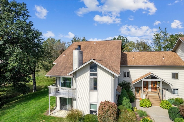 rear view of property with a balcony and a lawn