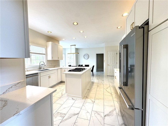 kitchen with white cabinetry, stainless steel appliances, sink, decorative light fixtures, and a center island