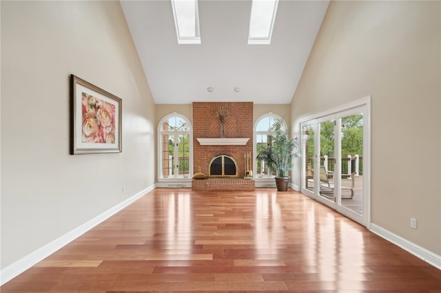 unfurnished living room featuring high vaulted ceiling, wood-type flooring, and plenty of natural light