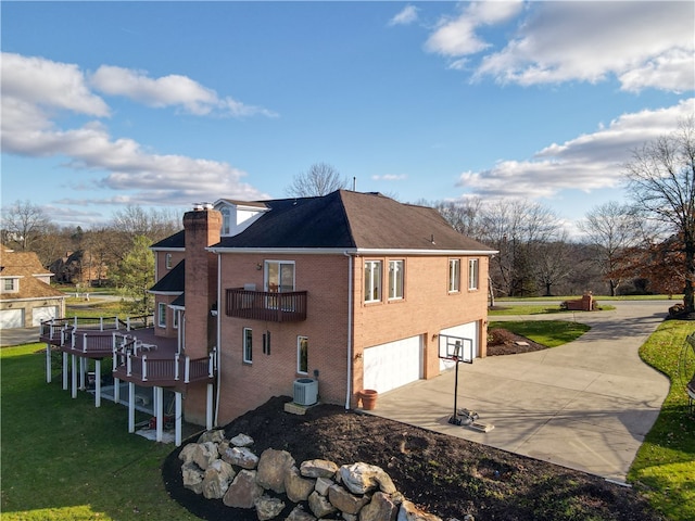 view of side of home featuring a balcony, central AC, a yard, and a garage