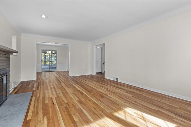 unfurnished living room featuring a notable chandelier, a fireplace, and light wood-type flooring