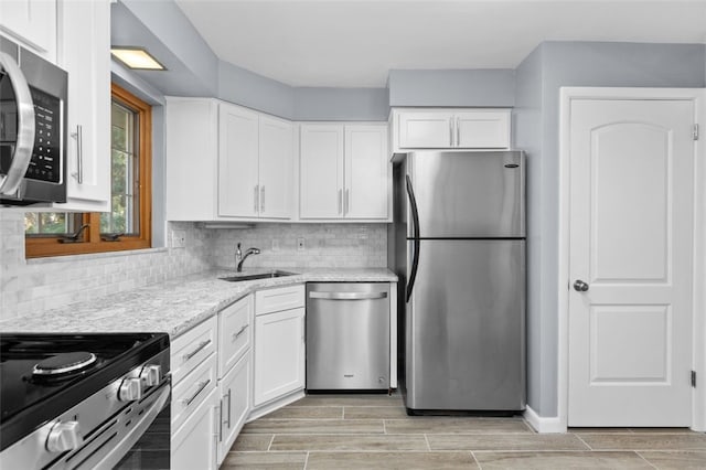 kitchen with white cabinets, backsplash, light hardwood / wood-style flooring, sink, and stainless steel appliances