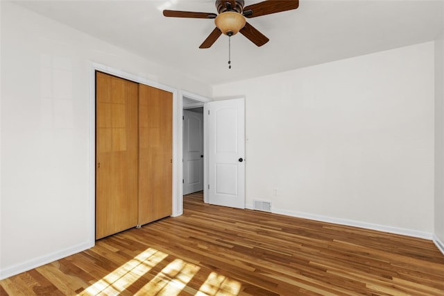 unfurnished bedroom with wood-type flooring, a closet, and ceiling fan