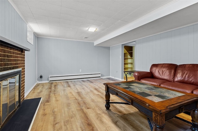 living room featuring wood walls, a baseboard radiator, a brick fireplace, ornamental molding, and light hardwood / wood-style flooring