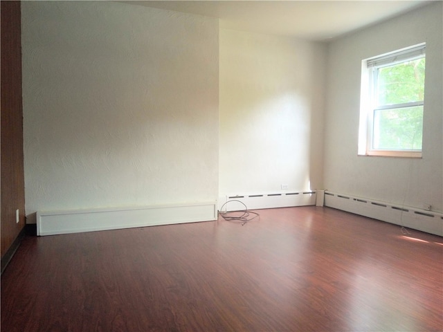 spare room with dark hardwood / wood-style floors and baseboard heating