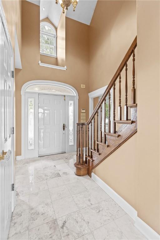 69 Orchard St, Carroll Twp, PA 15022 - foyer entrance with high vaulted ceiling, stairway, marble finish flooring, and baseboards
