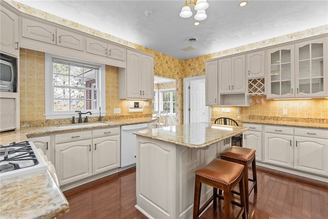 kitchen with white dishwasher, sink, white cabinetry, and dark hardwood / wood-style floors