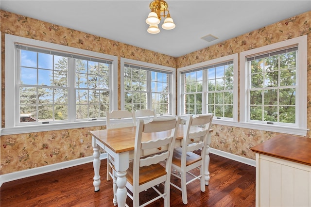 dining area featuring dark wood-type flooring, a healthy amount of sunlight, and an inviting chandelier