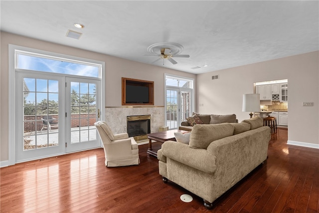 living room with dark wood-type flooring, ceiling fan, and a wealth of natural light