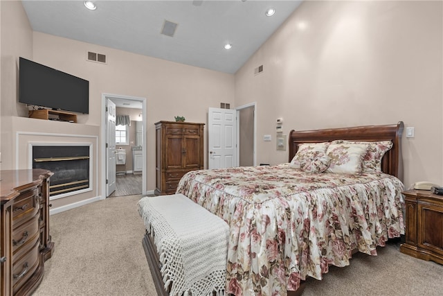 bedroom featuring light carpet, high vaulted ceiling, and connected bathroom