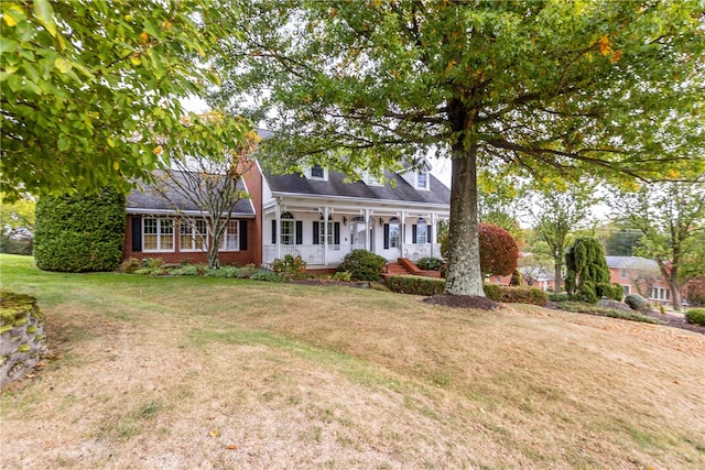 cape cod house with covered porch and a front lawn