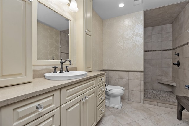 bathroom featuring tile walls, vanity, a tile shower, and toilet