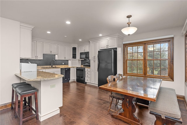 kitchen with dark hardwood / wood-style floors, sink, black appliances, decorative light fixtures, and white cabinets