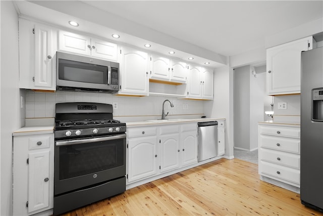 kitchen with appliances with stainless steel finishes, decorative backsplash, white cabinets, and light wood-type flooring