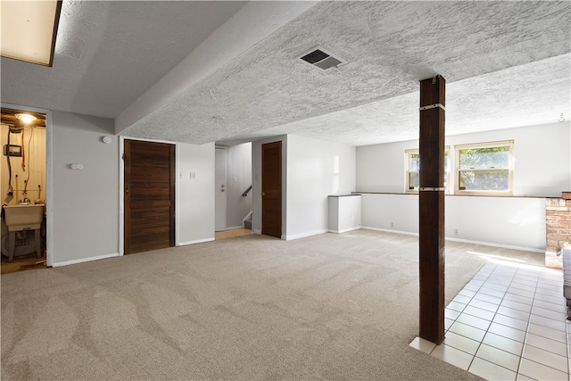 basement featuring light carpet, a textured ceiling, and sink