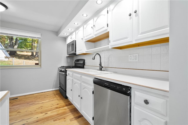 kitchen featuring stainless steel appliances, sink, light wood-type flooring, white cabinets, and tasteful backsplash