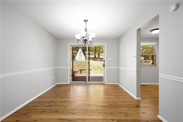 unfurnished dining area featuring a chandelier and hardwood / wood-style flooring