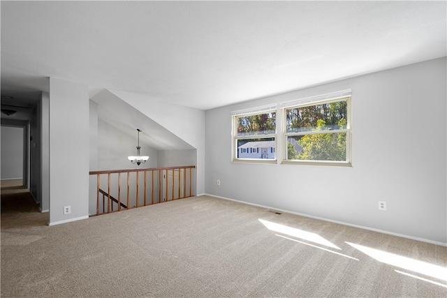 spare room featuring lofted ceiling, carpet, and an inviting chandelier