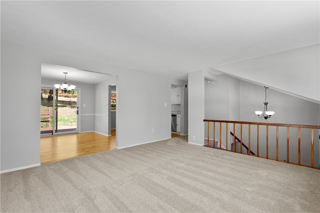 carpeted empty room featuring an inviting chandelier