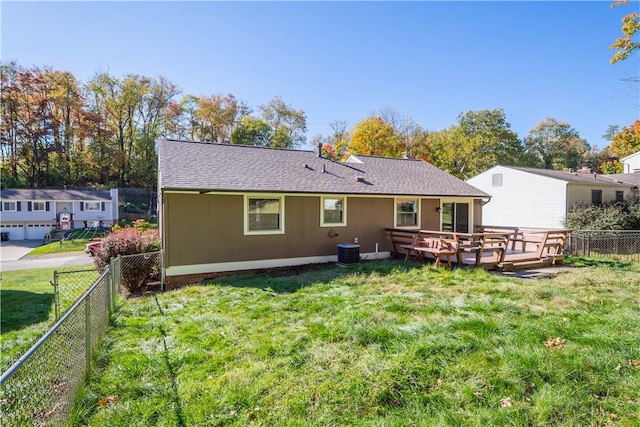 back of property with a yard, a deck, a garage, and central AC unit